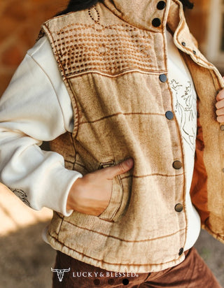 Tan denim puffer vest with studded snap buttons, embroidered yoke detail, and front pockets.