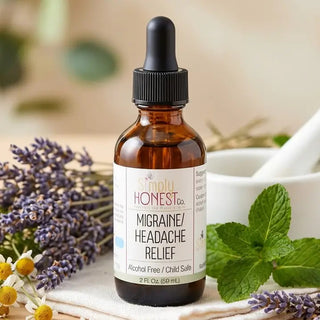 Amber dropper bottle of Simply Honest Co. Migraine Headache Relief tincture surrounded by lavender, chamomile, and fresh mint