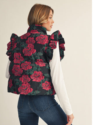 Black floral jacquard puffy vest with red roses, ruffled cap sleeves, worn over white long-sleeve top.