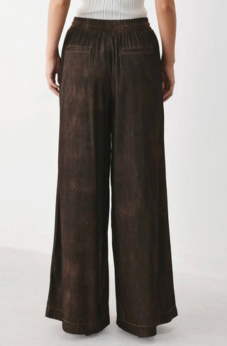 Dark brown wide-leg woven pants with elastic waistband, relaxed fit, and contrast stitching details.