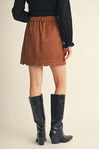 Brown faux suede mini skirt with scalloped hem and elastic waistband, styled with black boots.