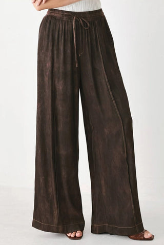 Dark brown wide-leg woven pants with drawstring waist, elastic band, and contrast stitching details.