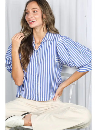 Blue and white striped button-down blouse with short puff sleeves, worn with cream trousers.