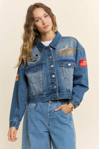 Medium wash denim jacket with Wild Ride embroidery and western patches, worn with wide-leg jeans.