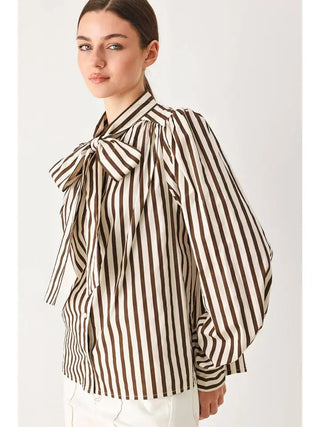 Brown and white striped oversized woven blouse with large statement bow detail at neckline.