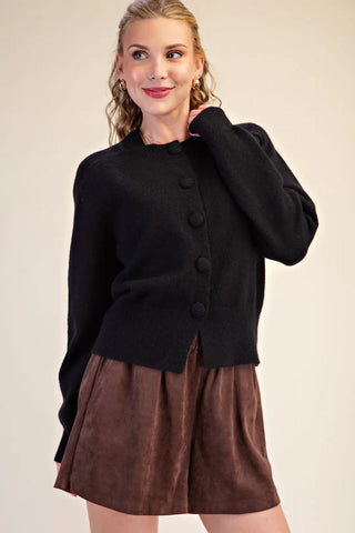 Black button closure long sleeve sweater cardigan paired with brown shorts on female model.