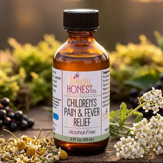 Amber glass bottle of Simply Honest Co. Children's Pain & Fever Relief, alcohol-free, surrounded by herbs and chamomile flowe
