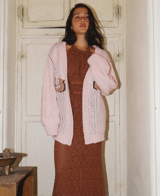 Light pink open knit cardigan with horse print pockets, worn open over a rust brown knit dress.