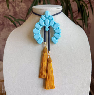 Baby blue naja pendant bolo tie with storm blue cord and golden yellow tassel fringe accents.