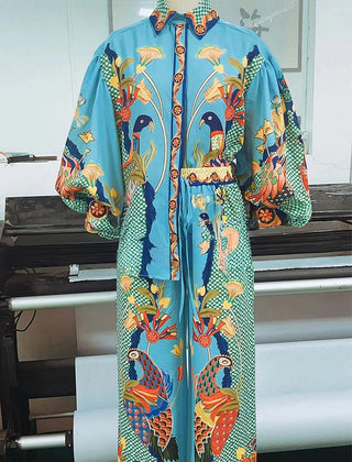 Turquoise blue peacock print two-piece set featuring colorful birds, floral motifs, long sleeves, and wide-leg pants.
