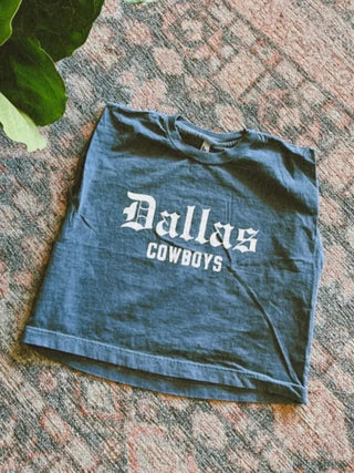 Dallas Cowboys muscle tank top in slate blue with white old English lettering, laid flat on rug.