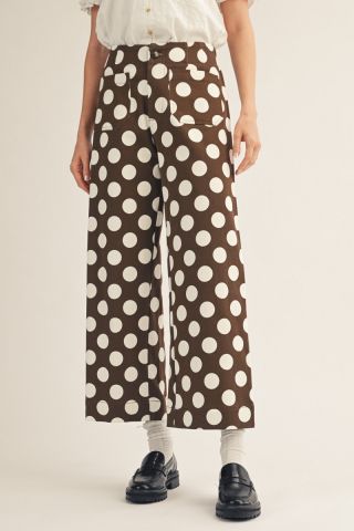 Brown wide-leg cropped pants with large white polka dots, styled with white socks and black loafers.