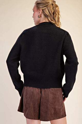 Black button closure long sleeve sweater cardigan shown from back, paired with brown suede mini skirt.