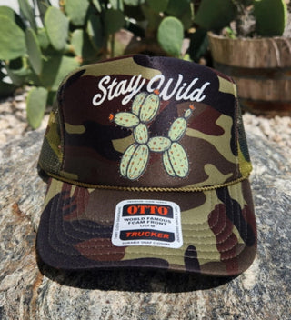 Camouflage trucker hat with "Stay Wild" text and cactus balloon animal graphic by OTTO.