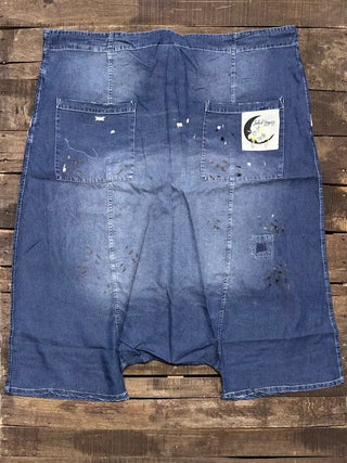 Distressed blue denim harem pants laid flat, featuring paint splatter details, multiple pockets, and Jaded Gypsy label.
