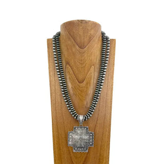 Double-strand silver Navajo pearl bead necklace with large engraved silver metal cross pendant on wooden display bust.