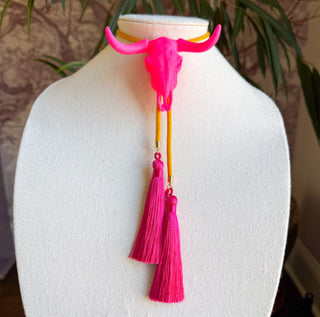 Neon pink longhorn bull skull bolo tie with golden yellow cord and fuchsia silk tassels on mannequin.