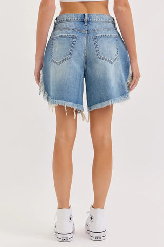 Mid waist light blue denim cut off shorts with frayed hem, two back pockets, worn with white Converse sneakers.