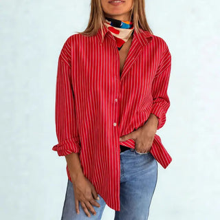 Women's oversized red and white pinstripe satin button-down shirt with long sleeves, paired with jeans.