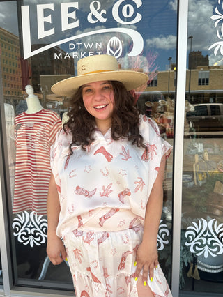 White placket shirred sleeve band top with pink cowboy boot and cactus print pattern, modeled outdoors.