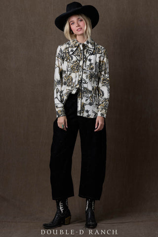 White printed western button-up shirt with black and gold floral pattern, worn with black wide-leg jeans and cowboy boots.