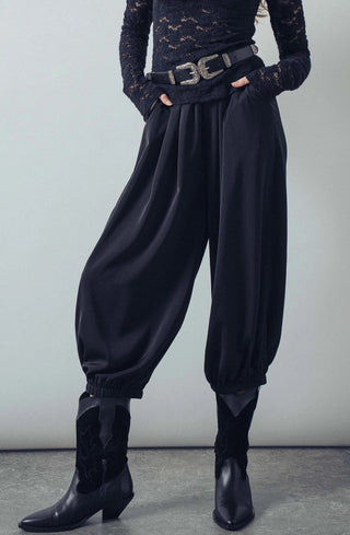 Black relaxed-fit boho pants with gathered elastic cuffs, worn with western belt and black cowboy boots.