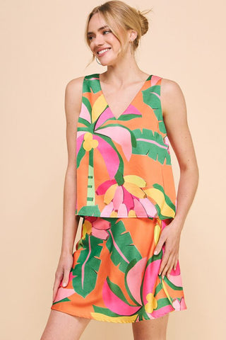 Tropical printed satin V-neck tank top in orange, green, pink, and yellow palm leaf pattern, styled with matching shorts.
