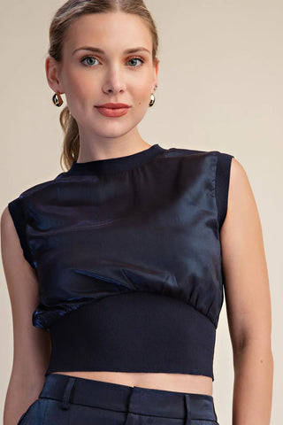 Navy blue sleeveless crop top with satin fabric panel and ribbed knit waistband trim detail.