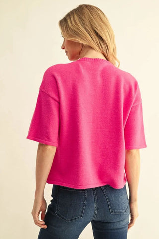 Hot pink drop shoulder short sleeve cropped sweater paired with dark blue jeans, back view.