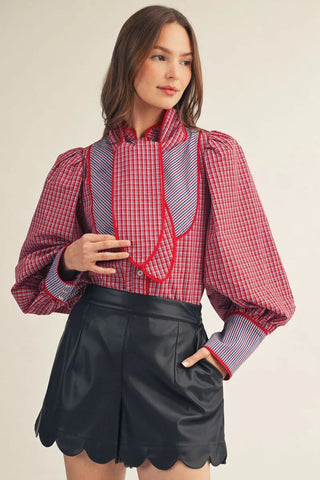 Red plaid puff sleeve button-down shirt with contrast bib front and red piping tie neck detail.