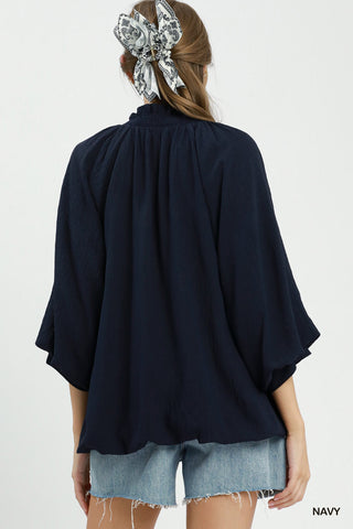 Navy balloon sleeve split neck blouse with smocked neckline, worn with denim cutoff shorts and paisley scrunchie.