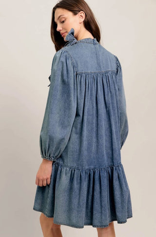 Light blue acid washed denim mini dress with tiered skirt, long balloon sleeves, and ruffled neckline detail.
