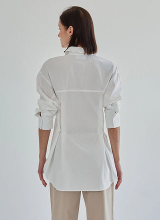 White oversized button-down shirt with back seam detail, worn by brunette model, shown from behind.