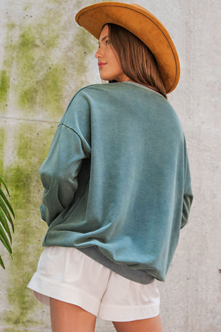 Teal snow washed oversized pullover sweatshirt with dropped shoulders, paired with white shorts and tan cowboy hat.