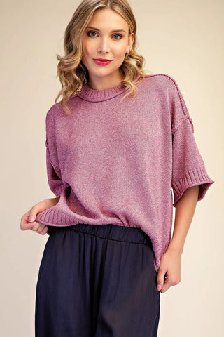 Mauve pink lurex metallic short-sleeve mock neck sweater with ribbed trim and exposed seam details.