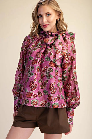 Magenta floral print blouse with ruffle bow neckline and long balloon sleeves, paired with brown shorts.