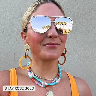 Shay Rose Gold aviator sunglasses with mirrored lenses and gold frame, worn by blonde woman outdoors.