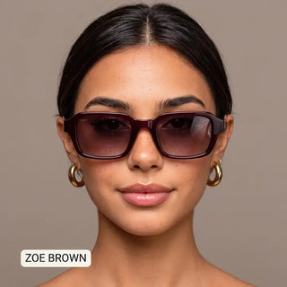 Woman wearing Zoe brown rectangular sunglasses with dark burgundy frames and gradient lenses, gold hoop earrings.