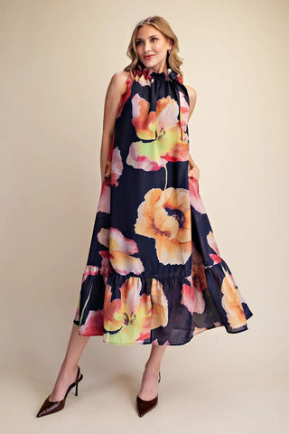 Navy blue sleeveless midi dress with bold watercolor floral print, ruffle neckline, and tiered hem.