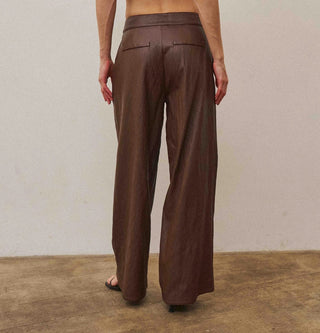 Chocolate brown wide-leg vegan leather pants shown from the back, featuring a tailored waistband.