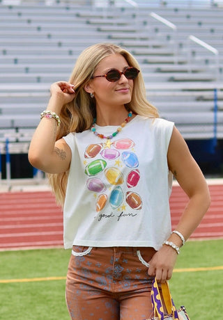 White sleeveless crop tank top featuring colorful rainbow football graphic print and "good fun" text.