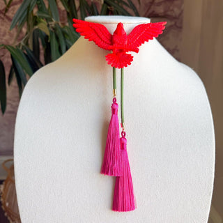 Red eagle bolo tie with olive green cord and two fuchsia silk tassels on white display bust.