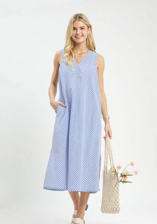 Blue and white chevron stripe sleeveless midi dress with V-neckline and side pockets, modeled with woven tote bag.