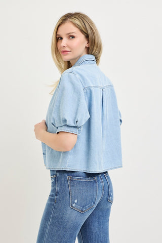 Light blue cropped denim shirt with puff short sleeves and button-front closure, styled with blue jeans.