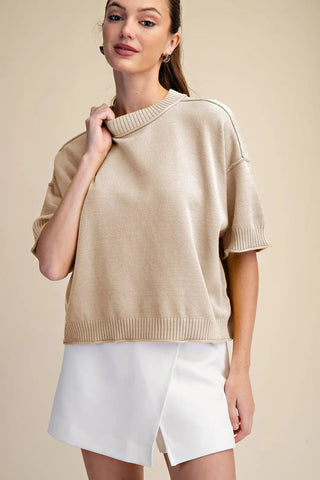 Beige relaxed-fit crew-neck sweater with elbow-length sleeves and ribbed trim detailing, styled with white shorts.