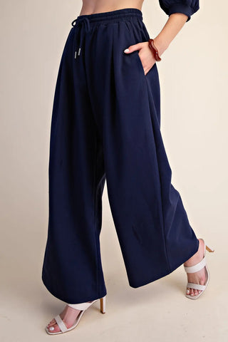 Navy blue wide-leg drawstring sweatpants with elastic waistband and side pockets, styled with heels.