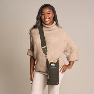 Woman wearing a forest green corduroy crossbody HydroBag with gold hardware over a beige turtleneck sweater.