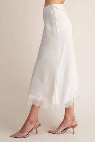 White satin midi skirt with delicate lace trim hem, paired with crystal embellished slingback heels.