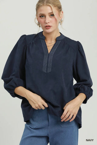 Navy sueded split neck blouse with contrast stitching detail, puff sleeves, and relaxed fit.