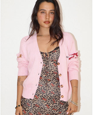 Pink knit cardigan with red Lucky baby horse embroidery, worn open over a leopard print dress.